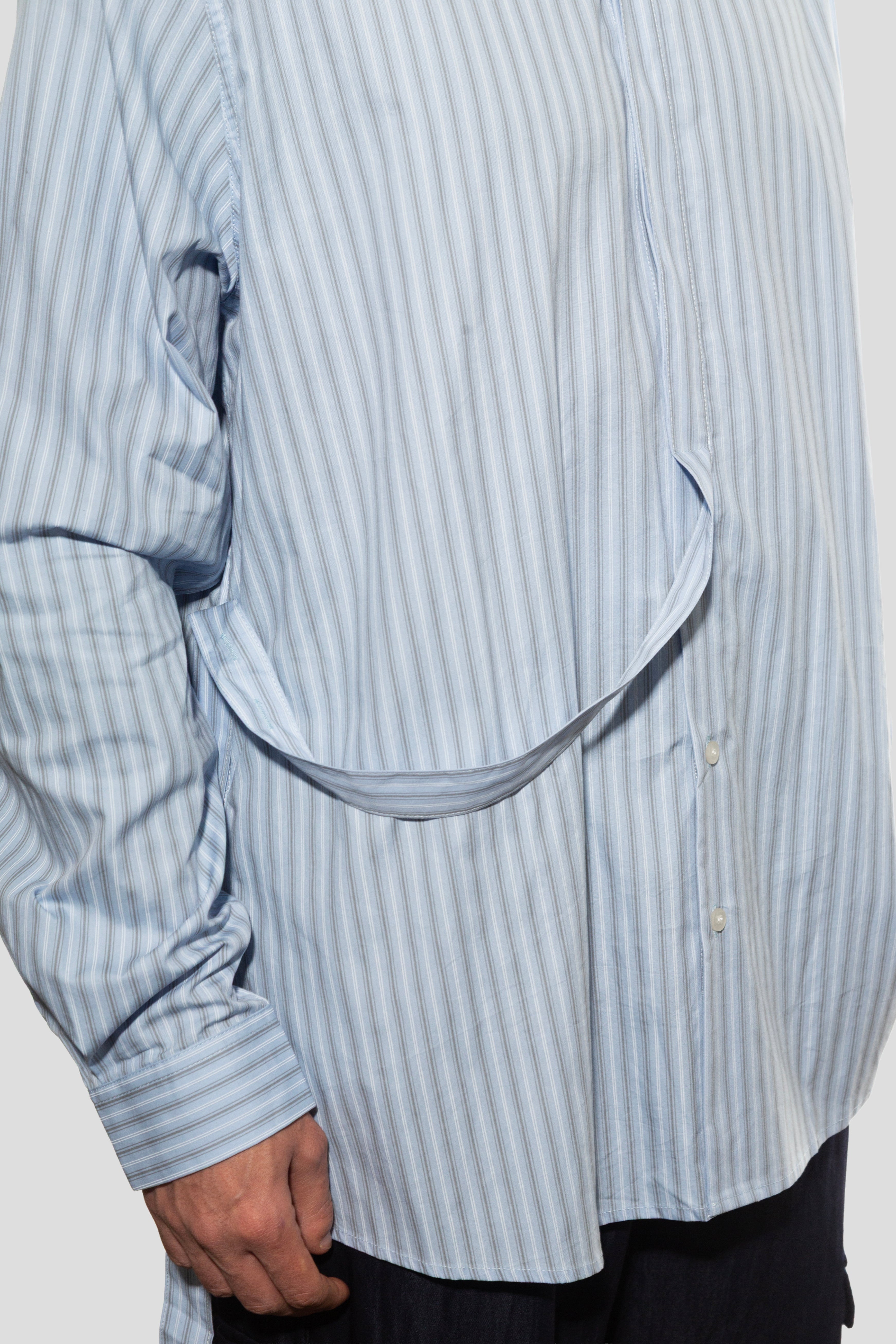 Close-up of a person wearing a light blue striped shirt with a large circular cutout on a white background
