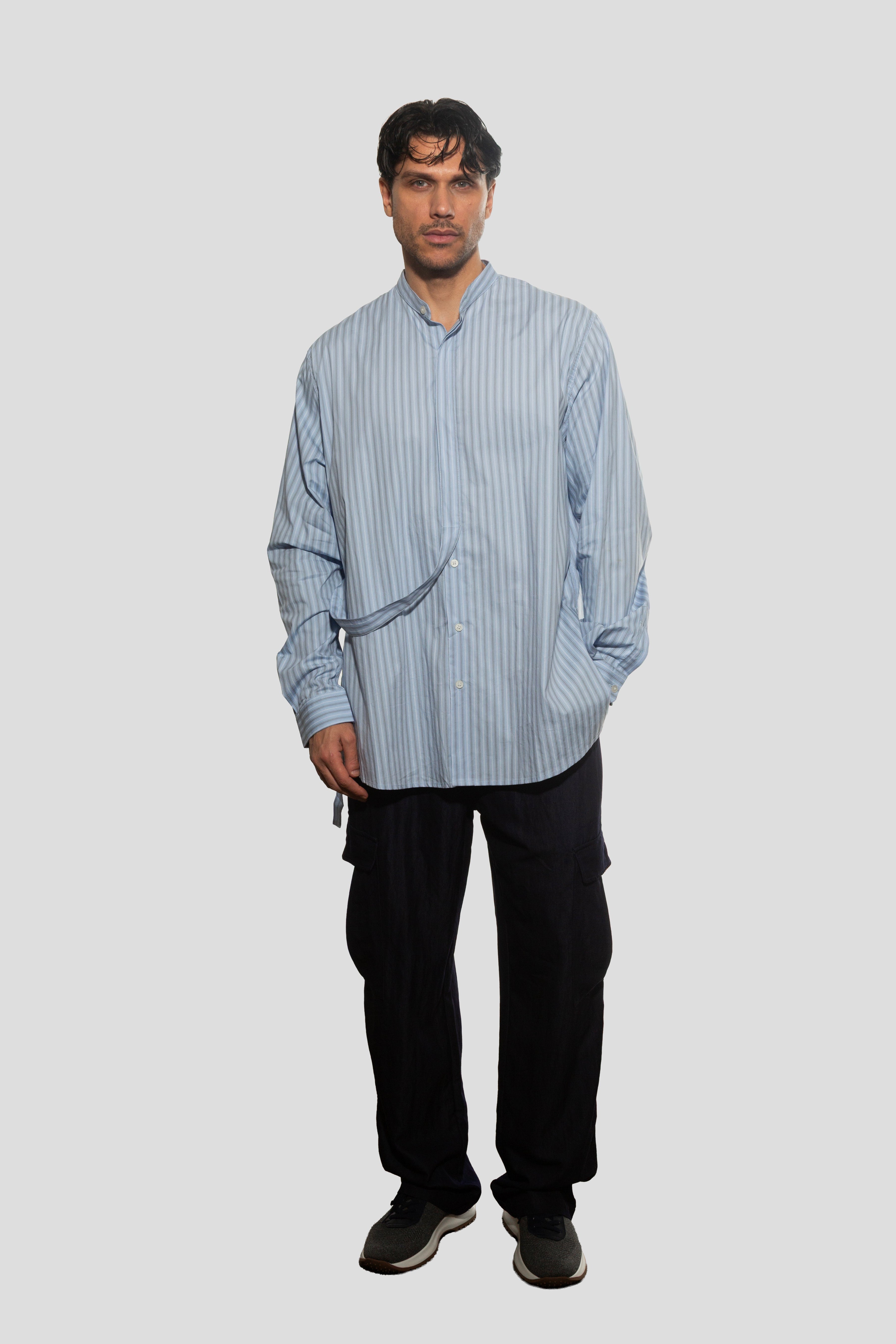 Man wearing a blue striped shirt and black pants on a white background