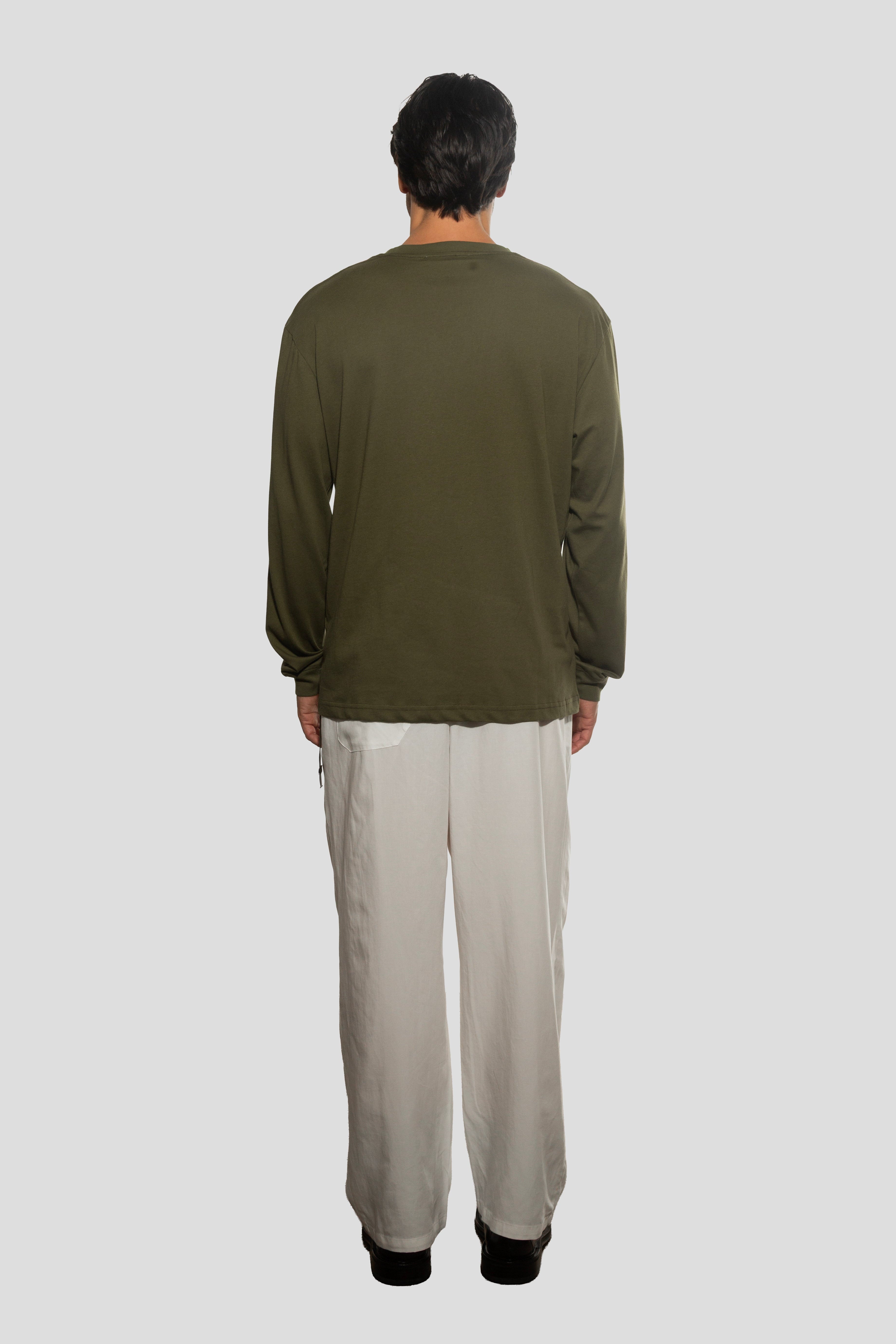 Person wearing a green long-sleeve shirt and beige pants on a white background