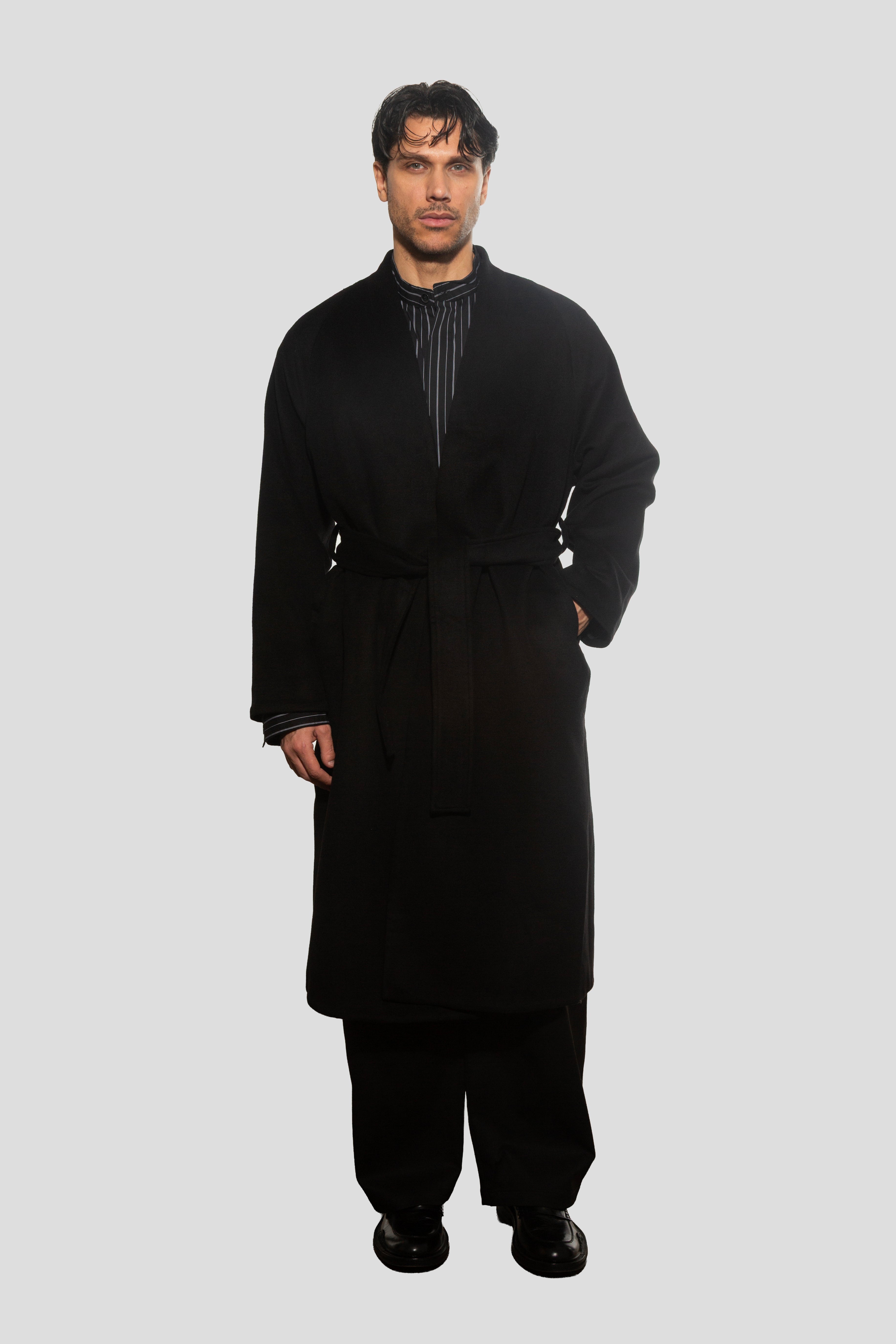 Man wearing a black coat and pants on a white background