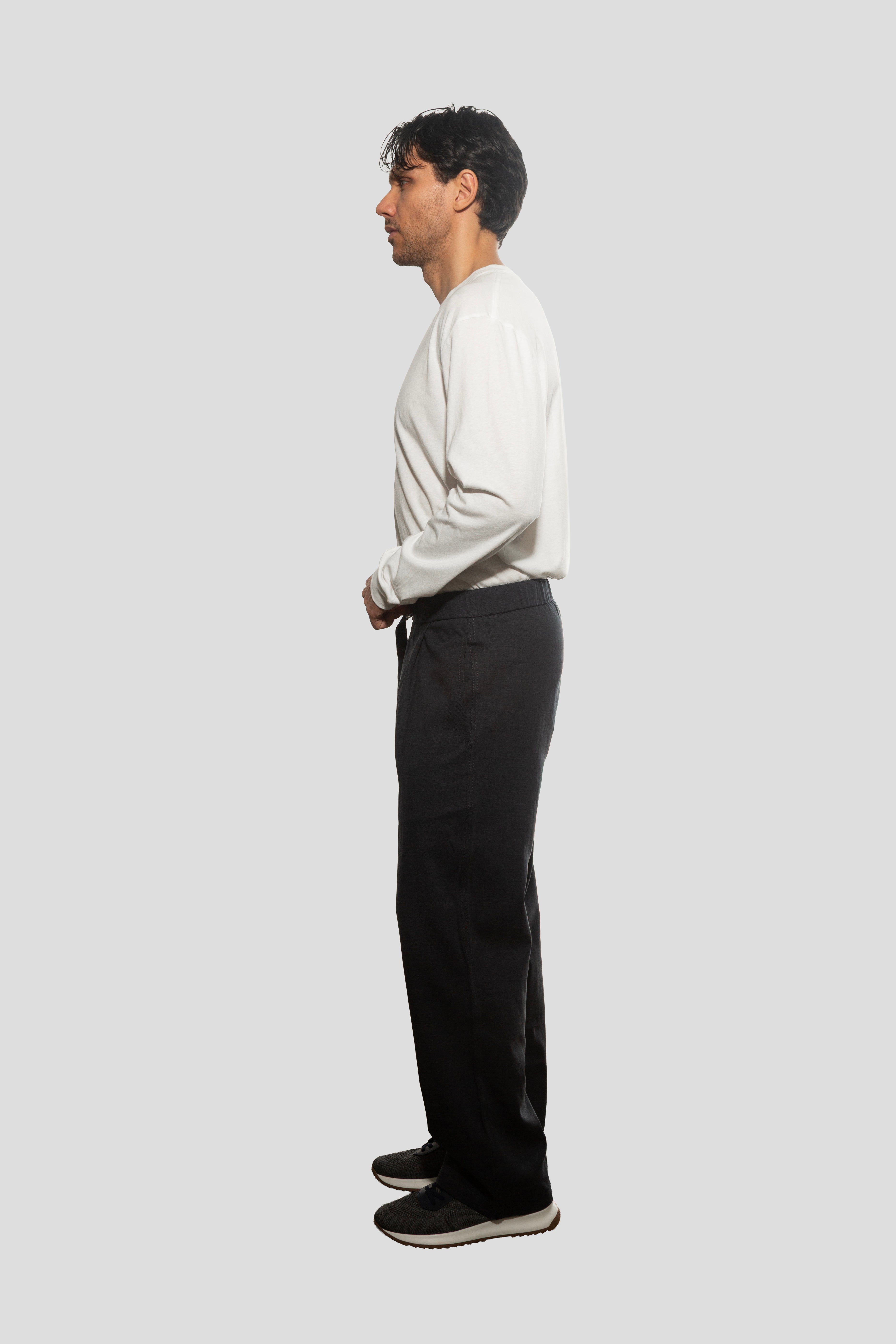 Person wearing a white shirt and black pants on a light gray background