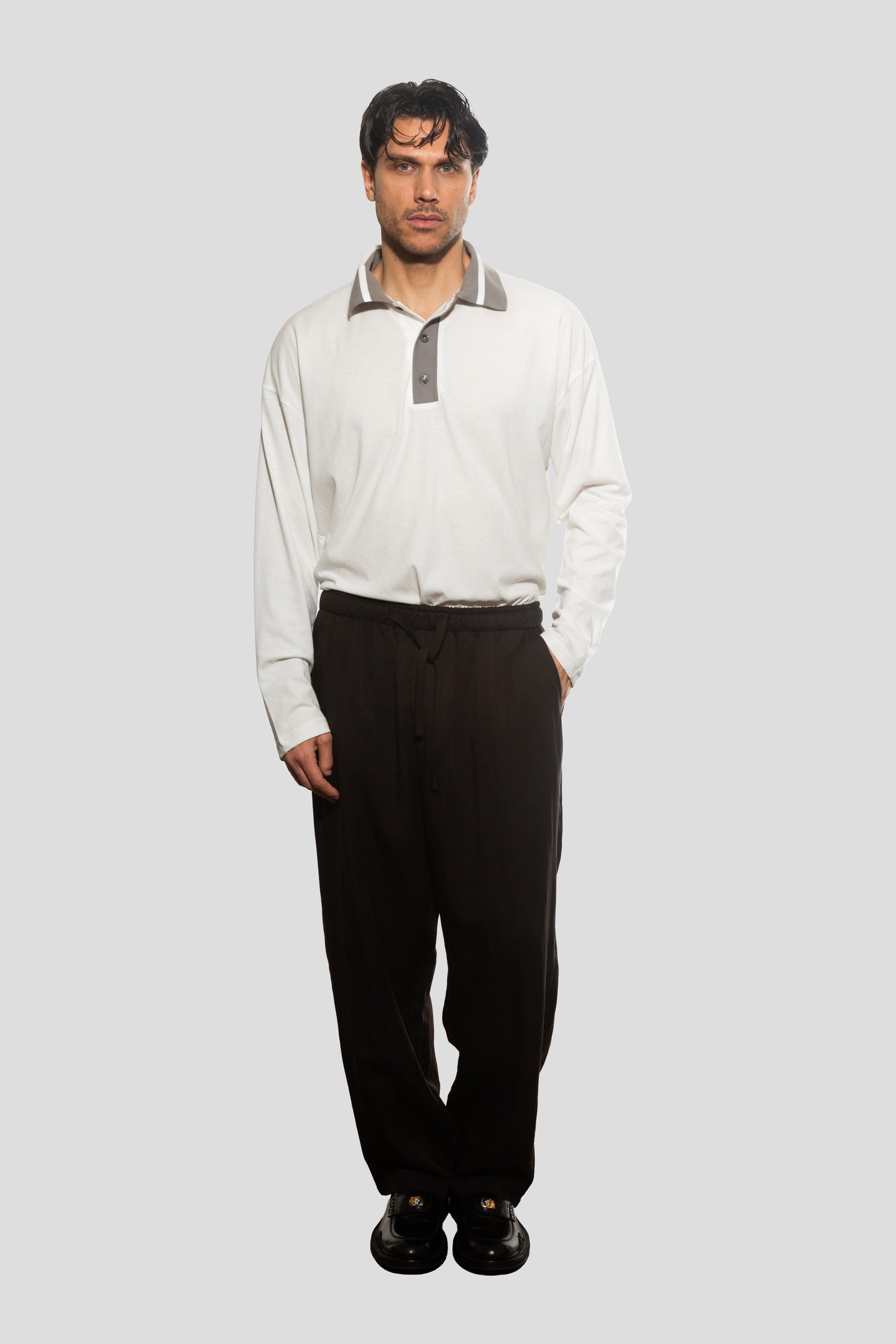 Man wearing a white shirt with gray collar and black pants on a white background