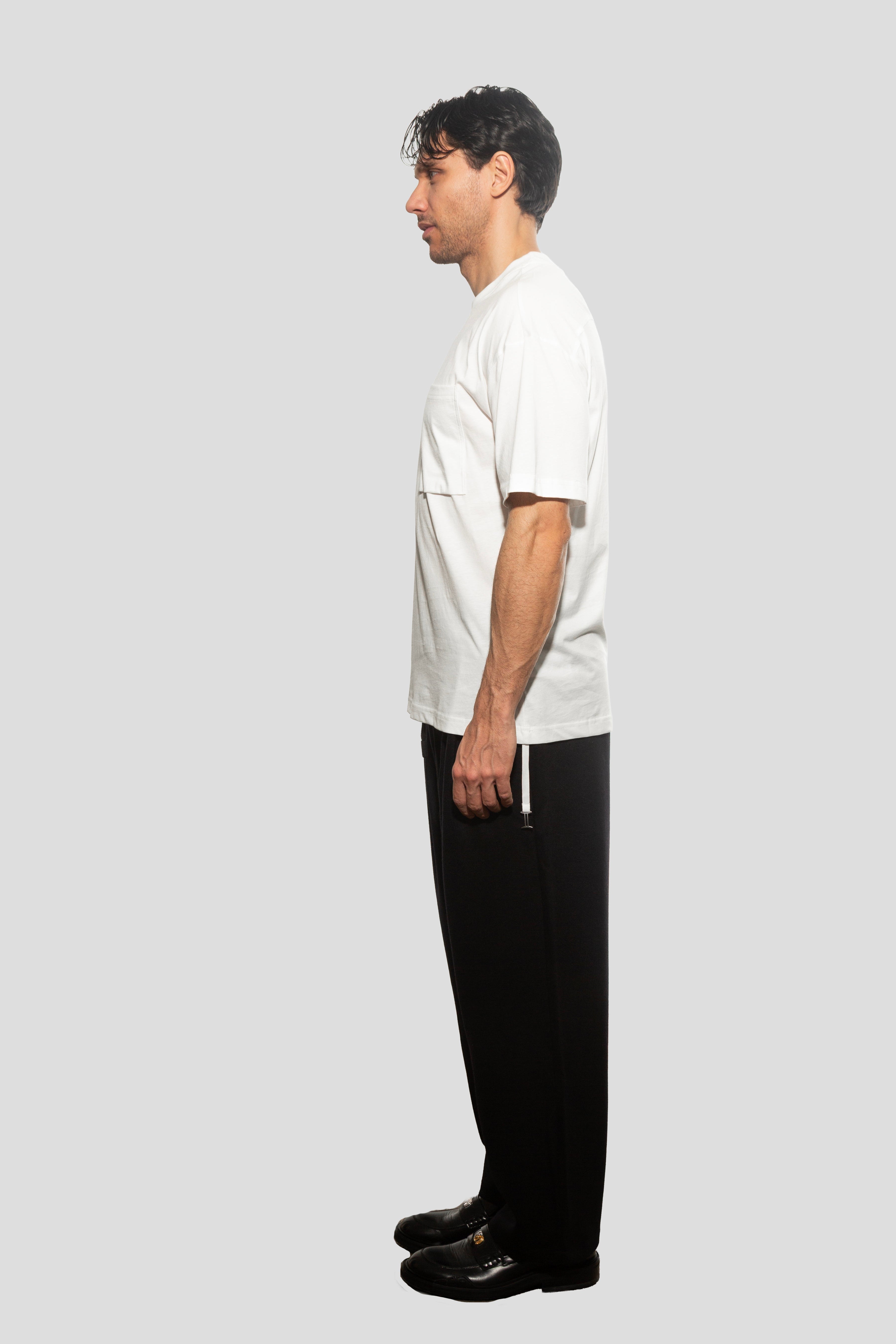 Person wearing a white t-shirt and black pants on a light gray background