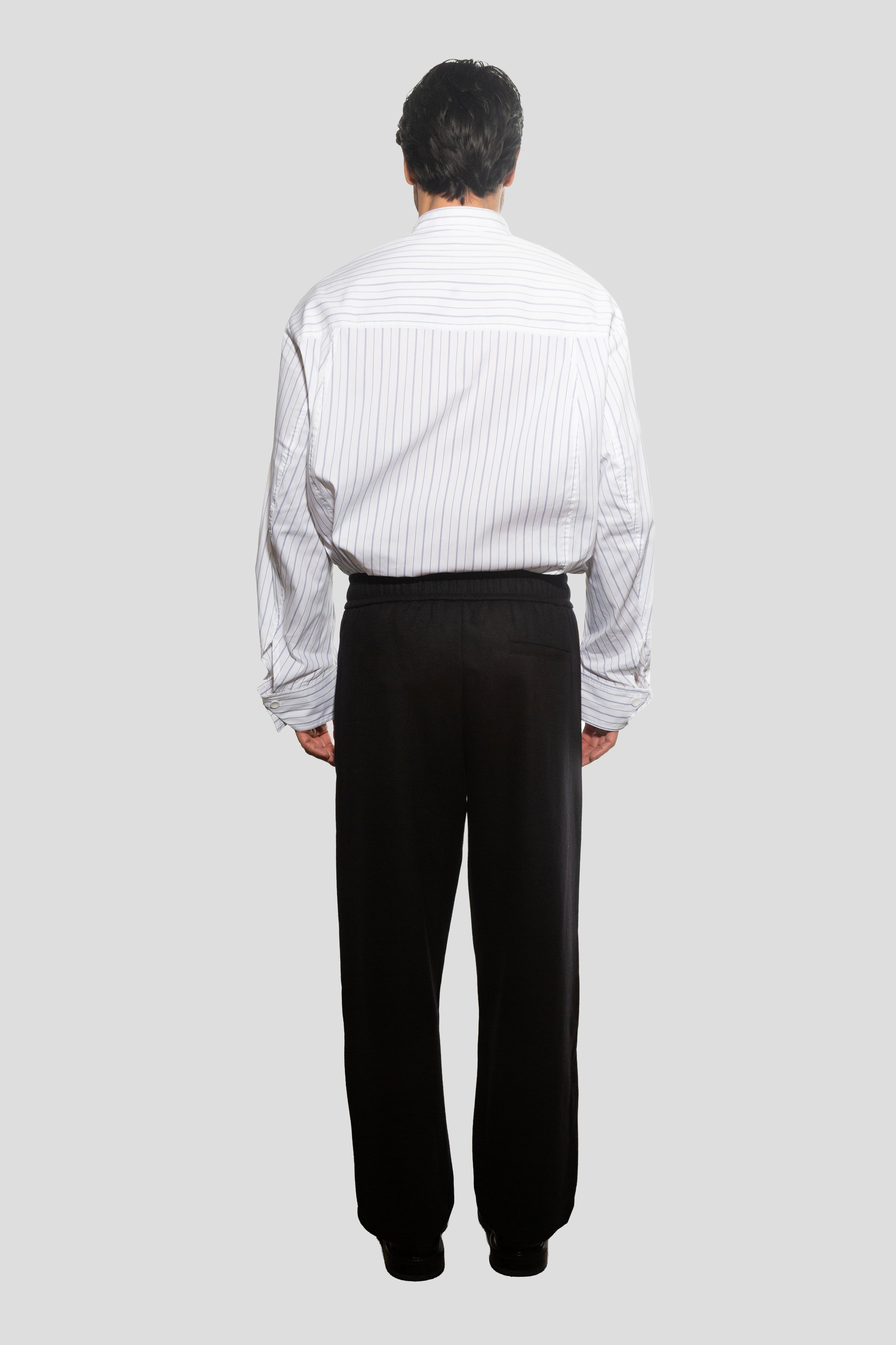 Person wearing a white shirt and black pants on a light gray background