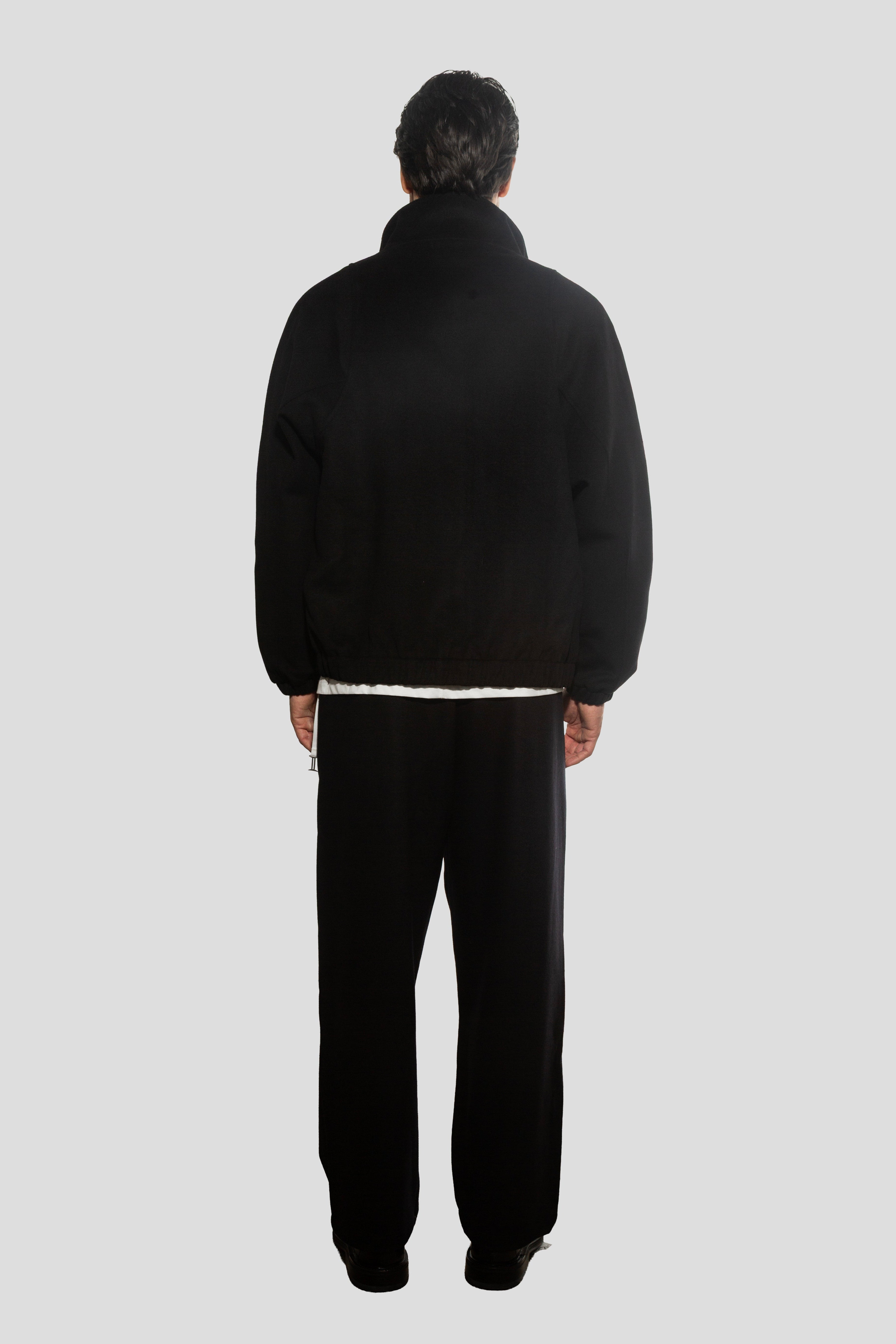 Person wearing a black tracksuit on a white background