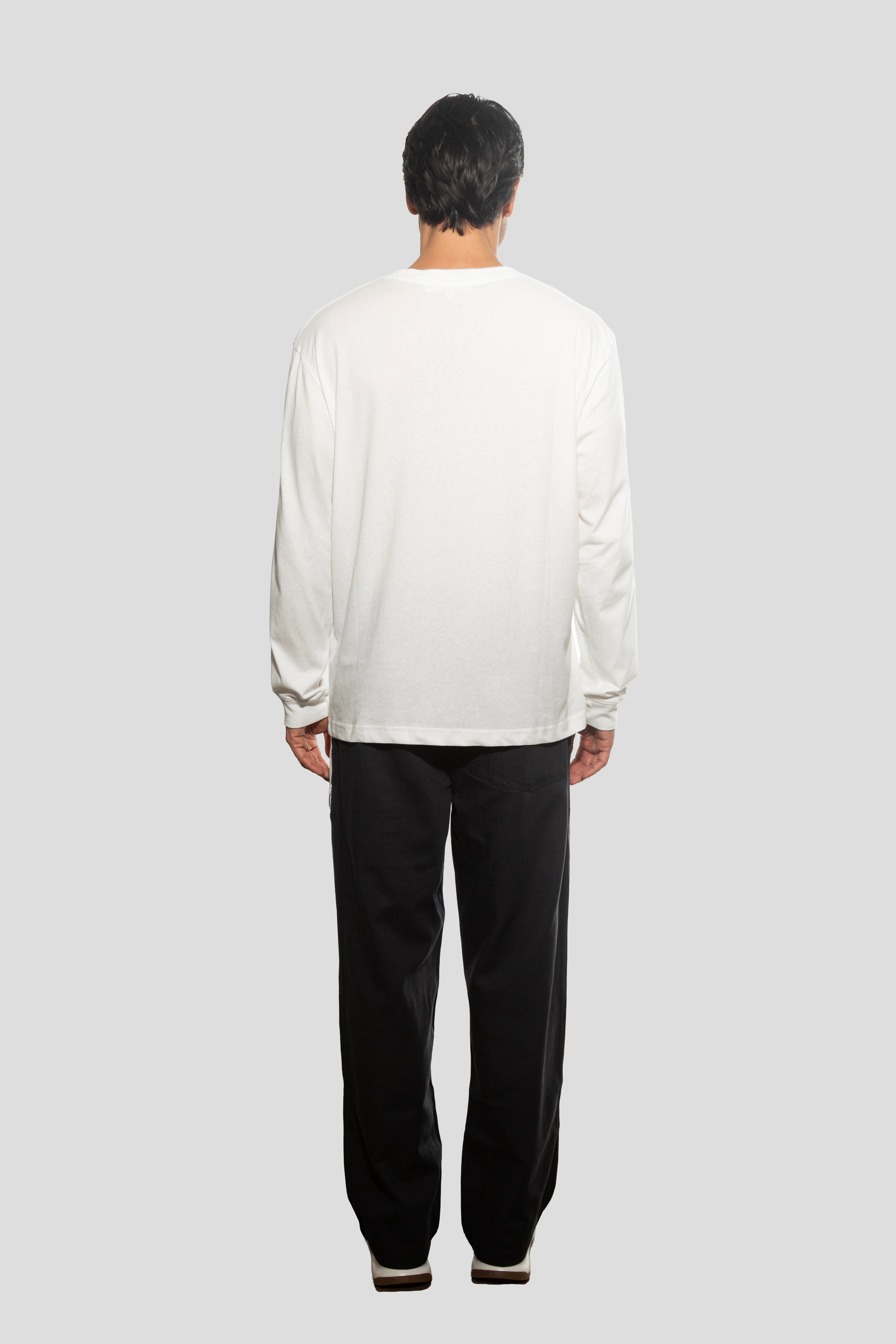 Person wearing a white long-sleeve shirt and black pants on a light gray background