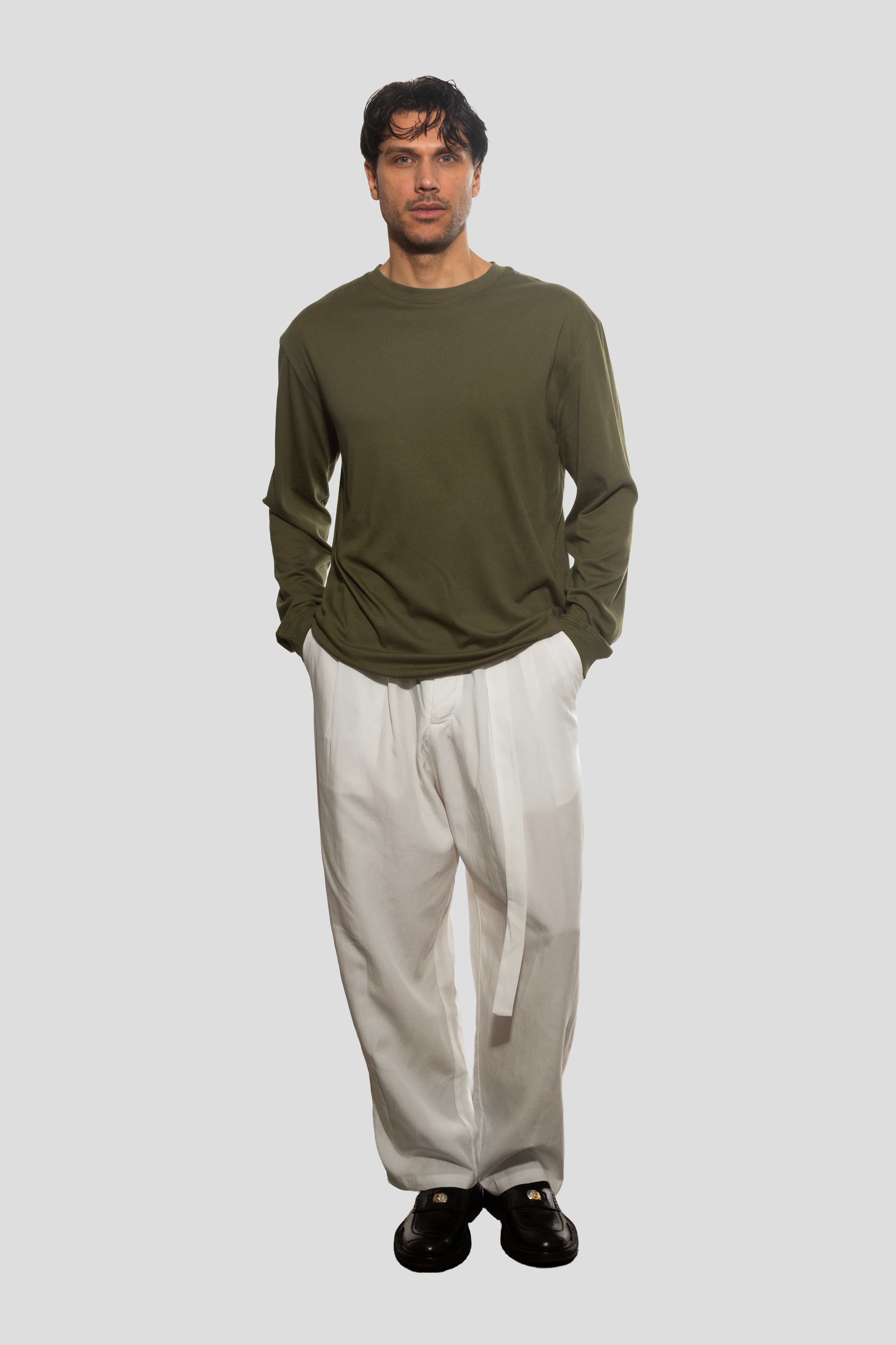 Man wearing a green long-sleeve shirt and white pants on a light gray background