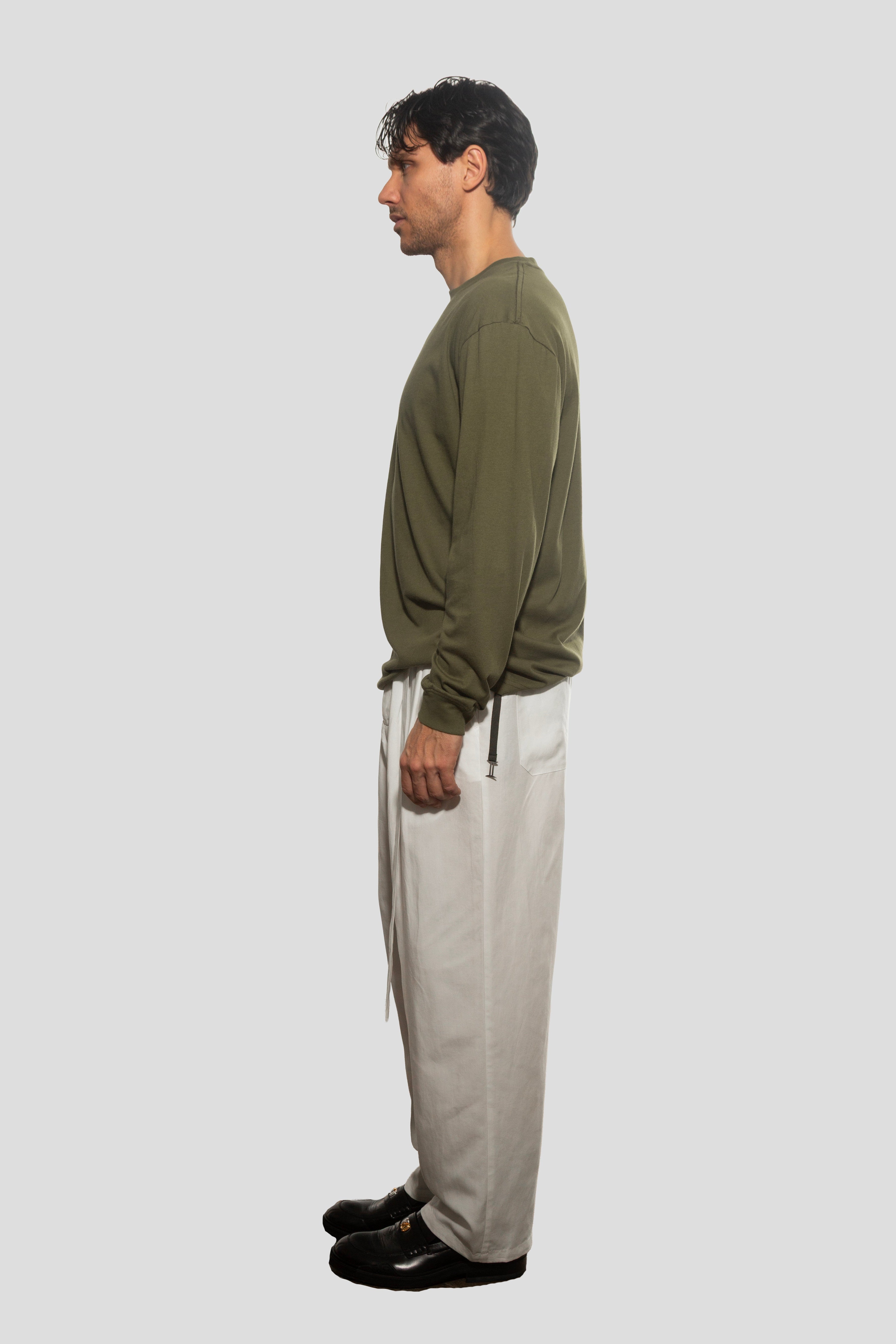Man wearing a green sweater and beige pants on a white background