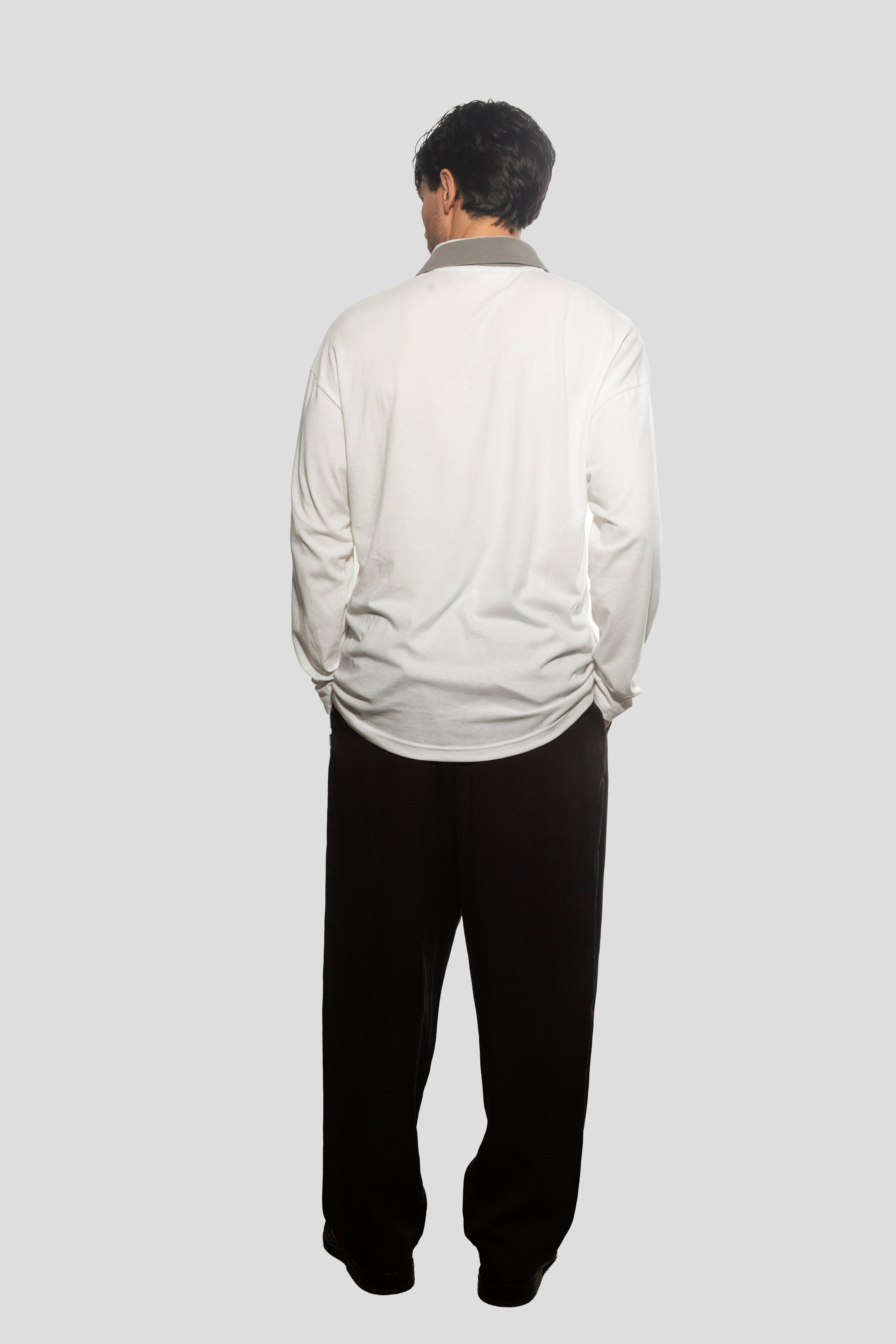 Person wearing a light-colored jacket and dark pants on a white background