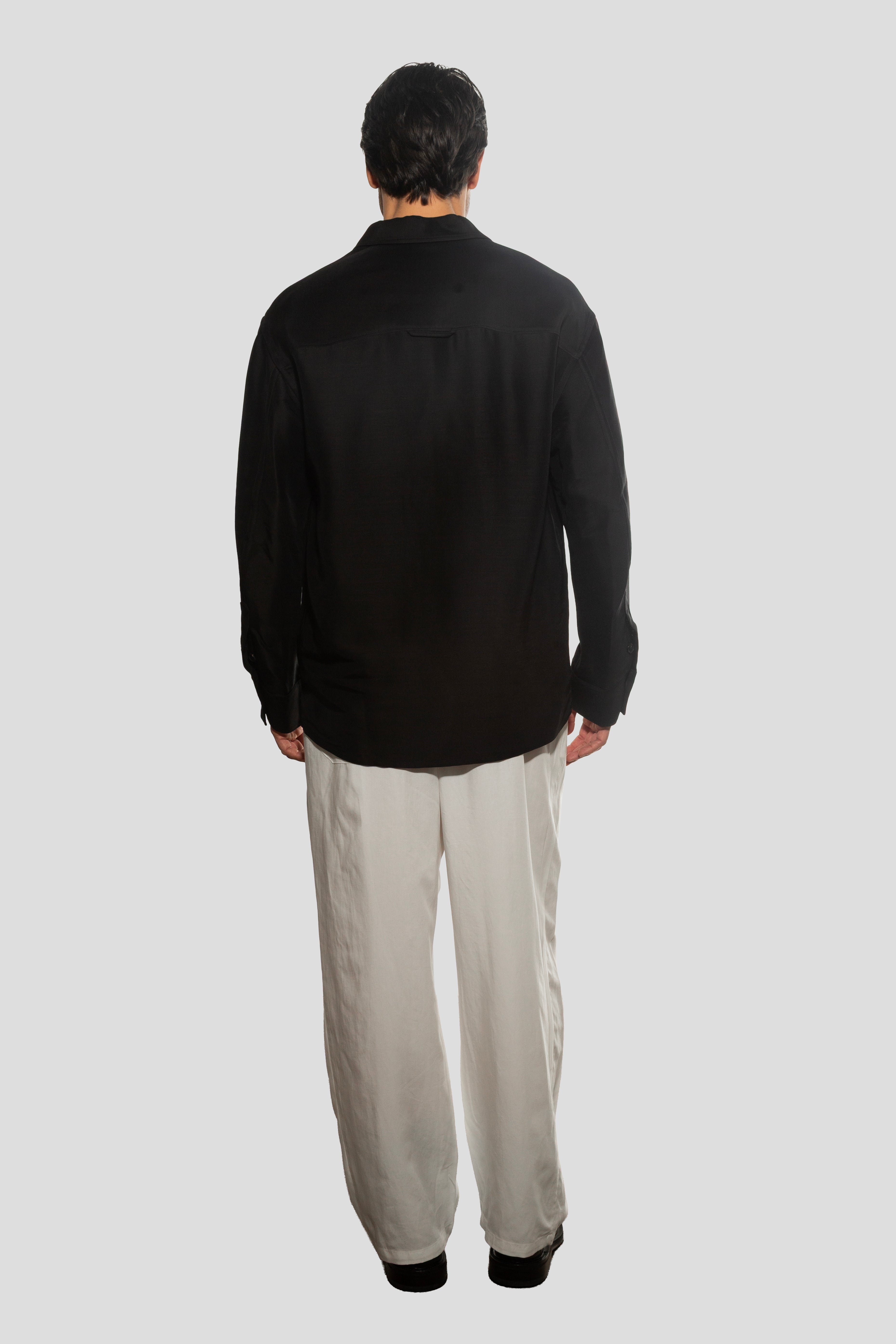Person wearing a black shirt and beige pants on a white background
