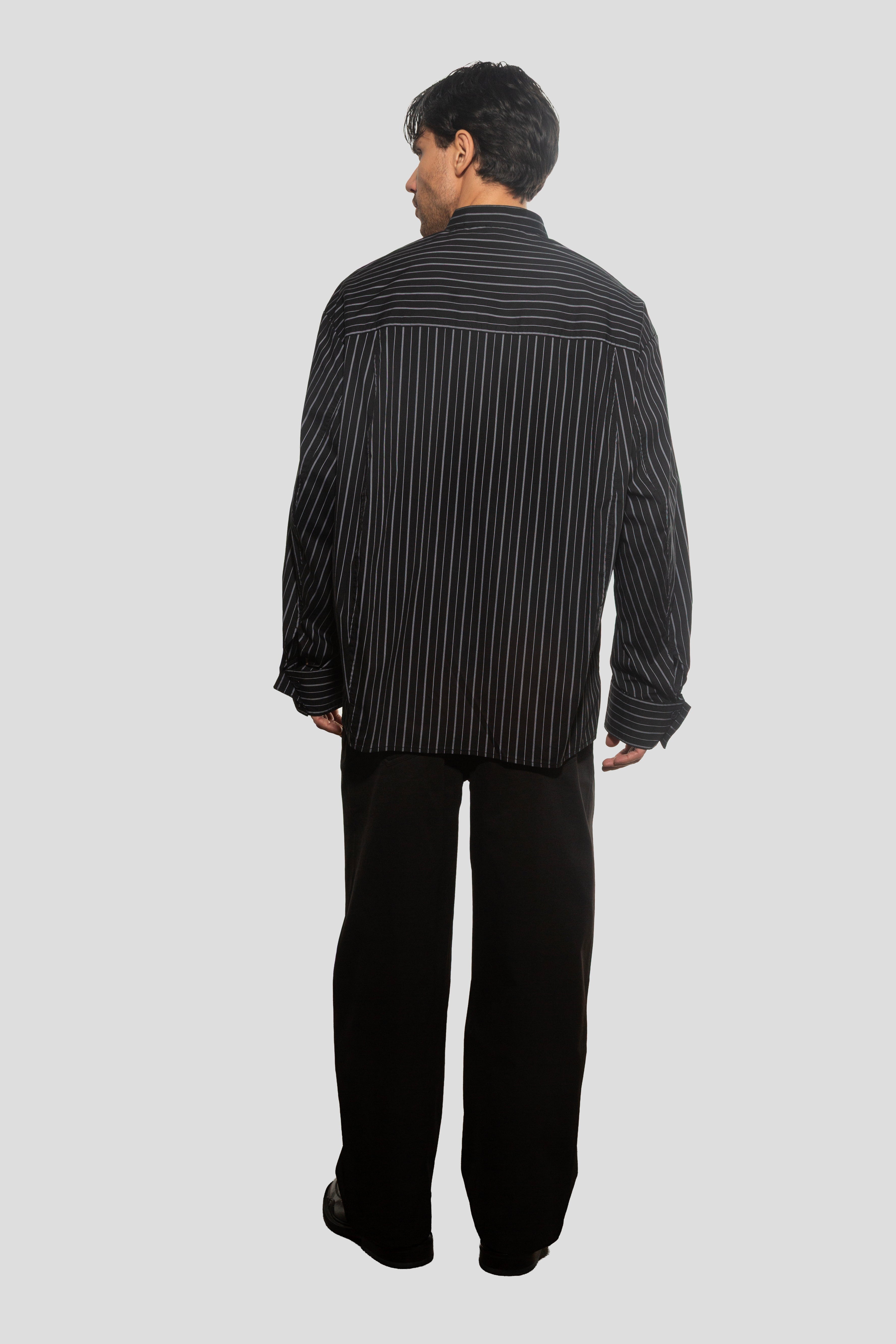 Person wearing a black and white striped shirt and black pants on a light gray background