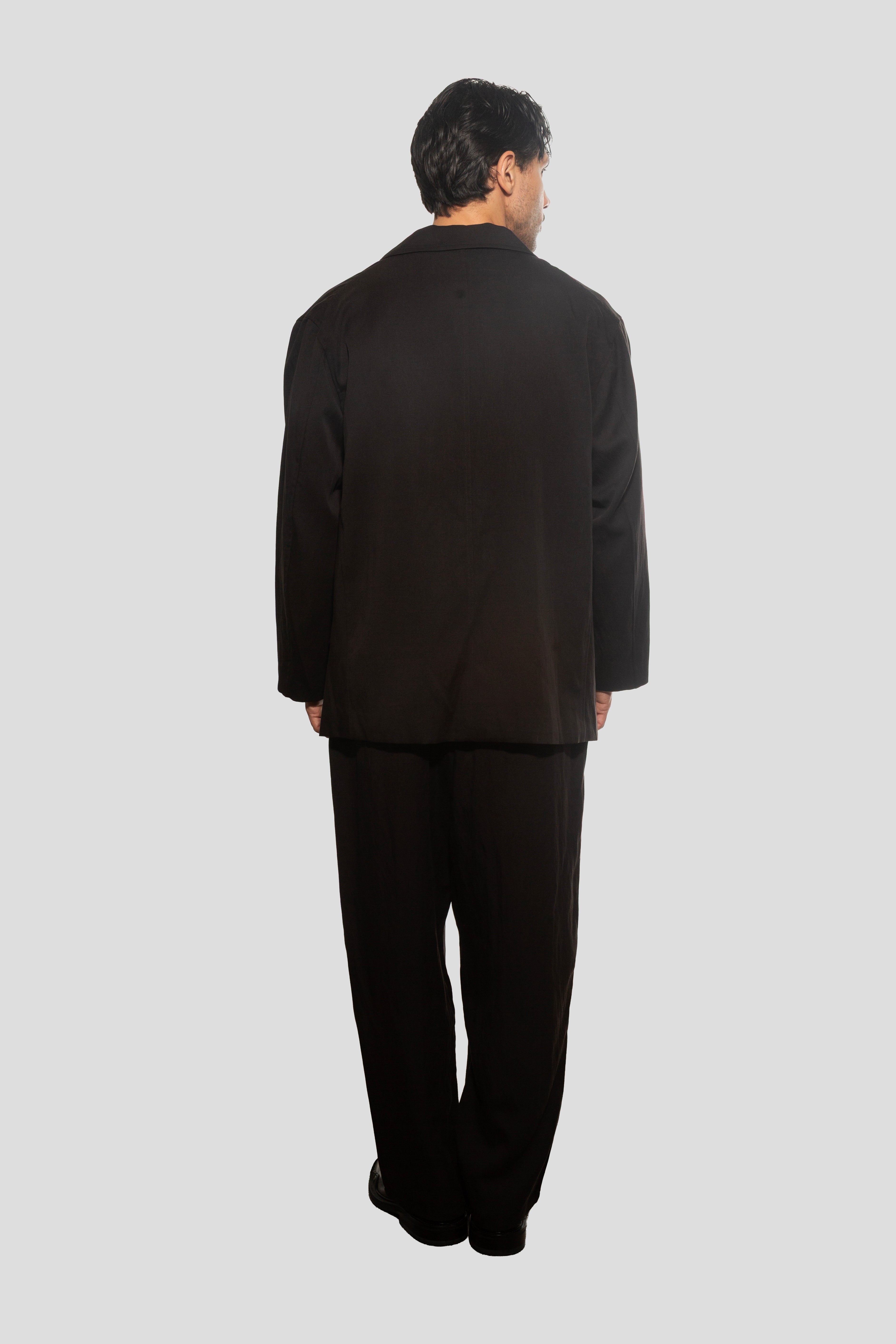 Person wearing a black suit on a light gray background