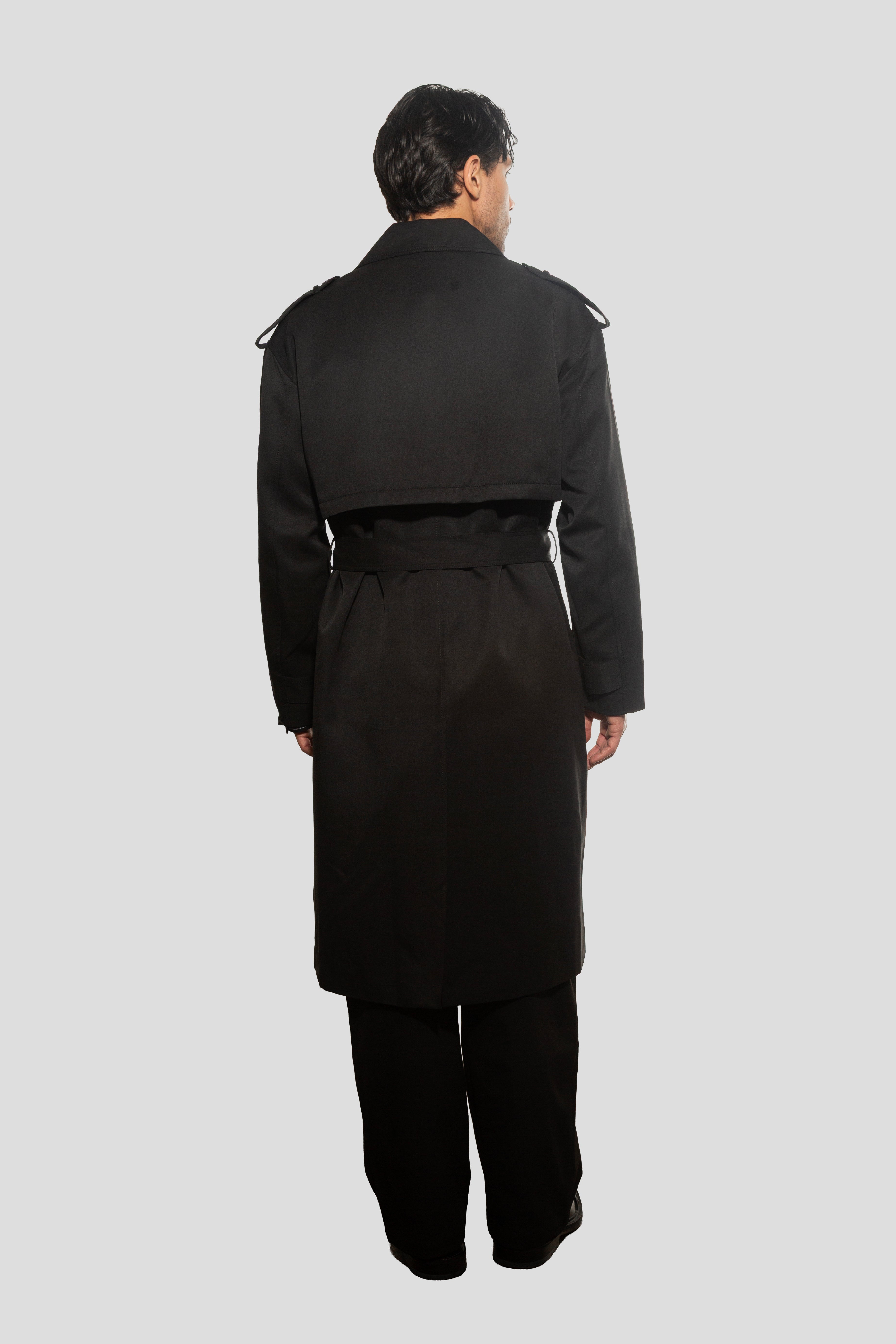 Person wearing a black trench coat on a white background