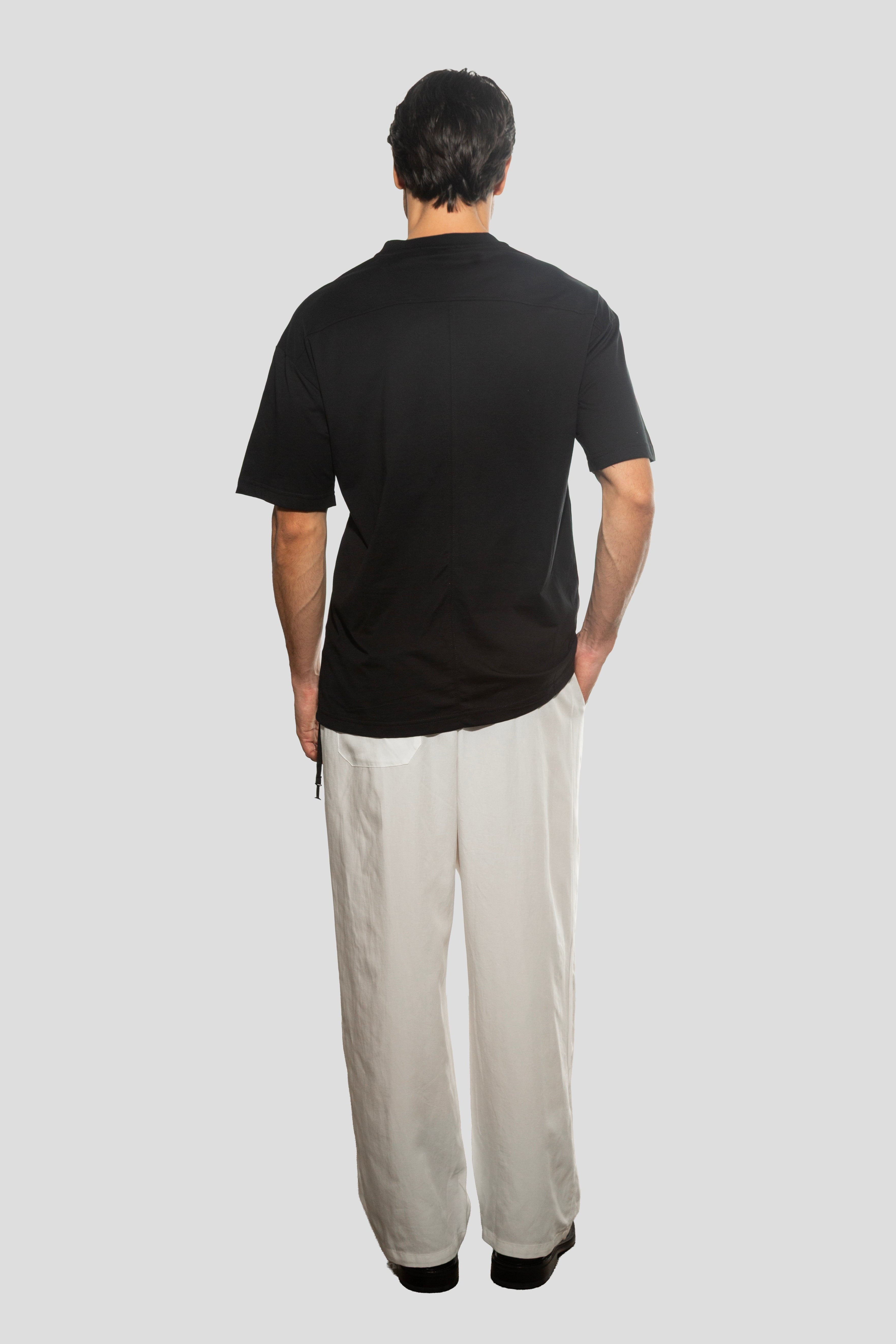 Person wearing a black t-shirt and light-colored pants on a white background