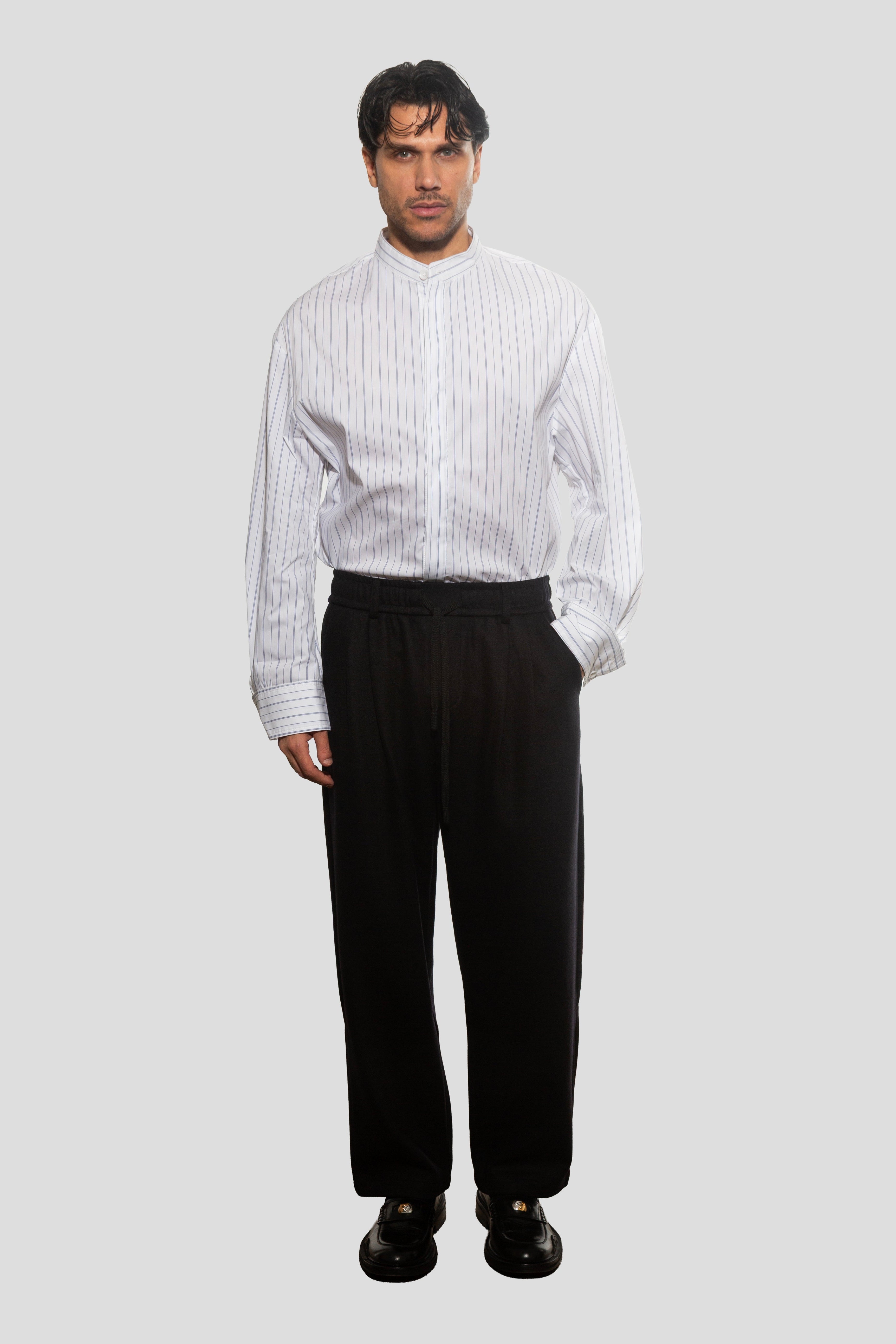 Man wearing a white pinstripe shirt and black pants on a light gray background