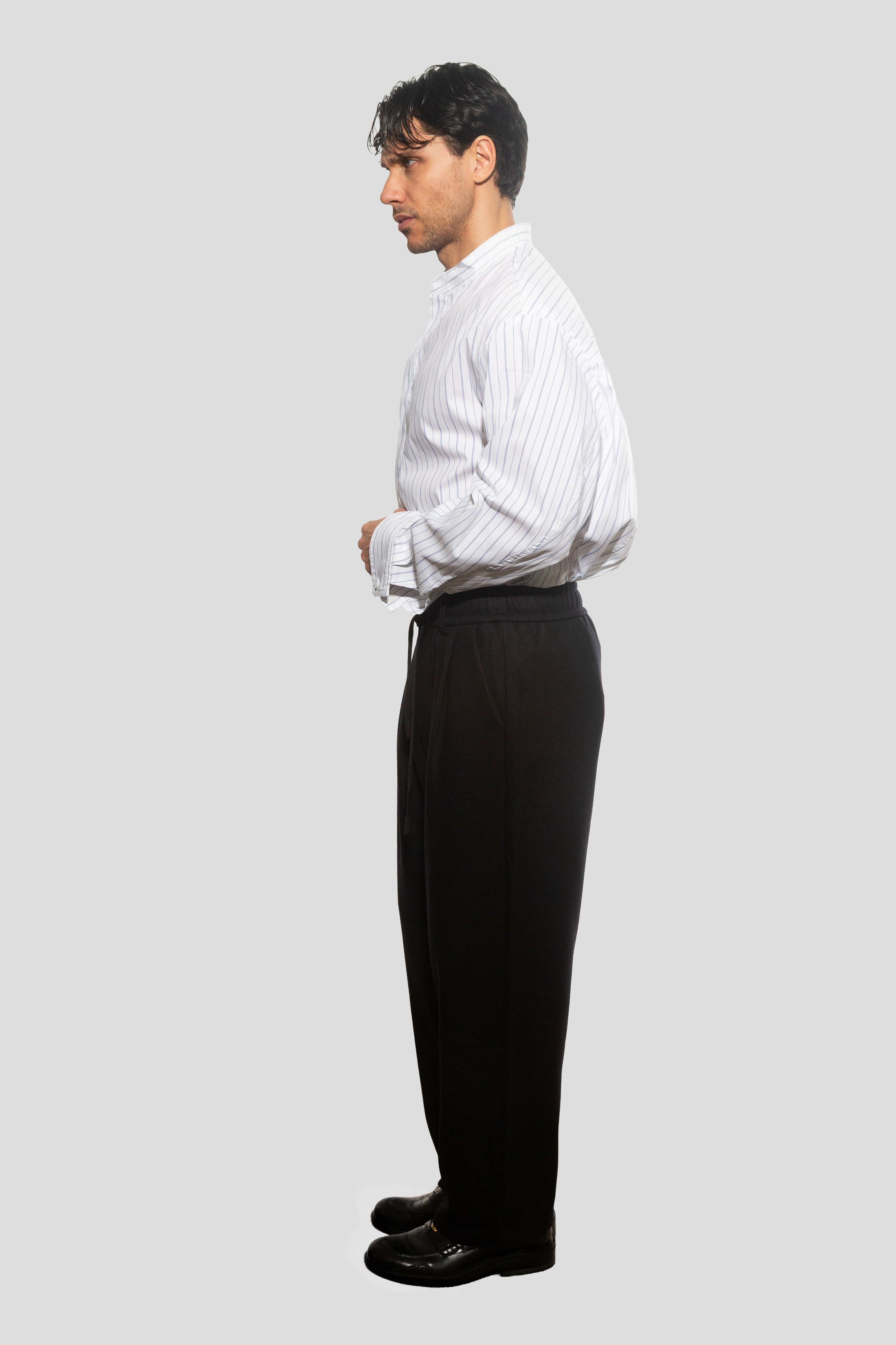 Man wearing a white dress shirt and black pants on a light gray background